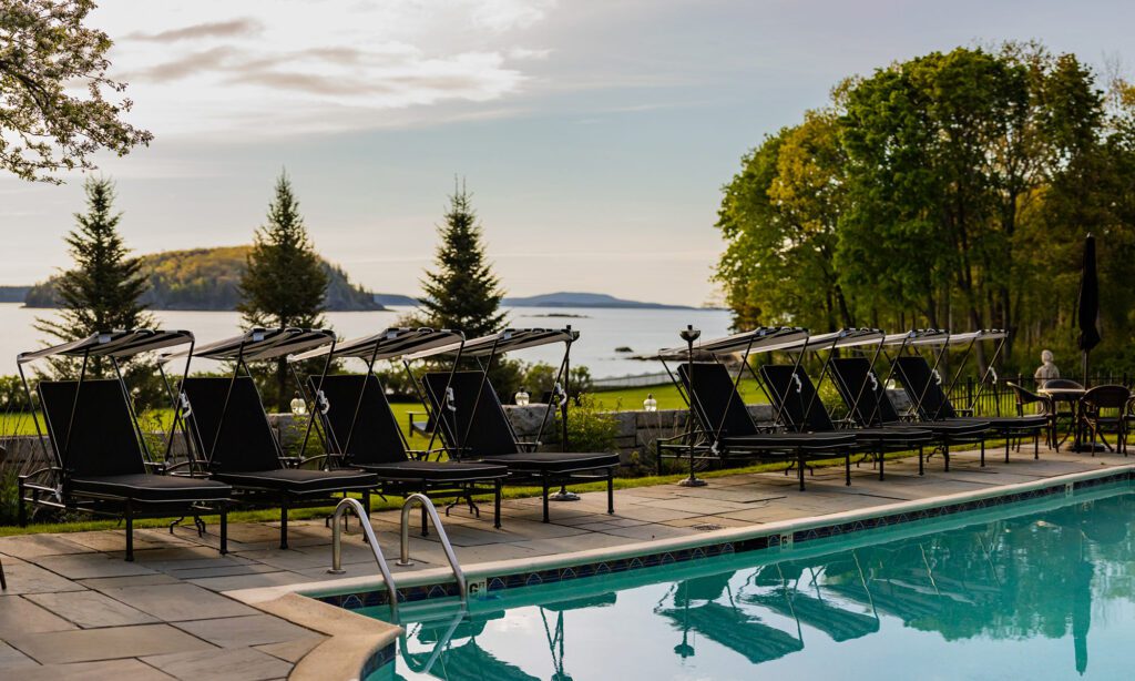 A swimming pool and lounge chairs with an ocean view